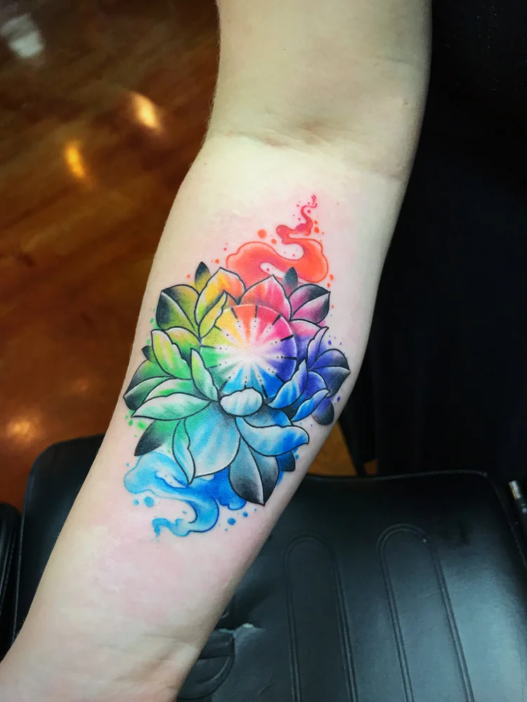 Rainbow lotus flower tattoo on the forearm